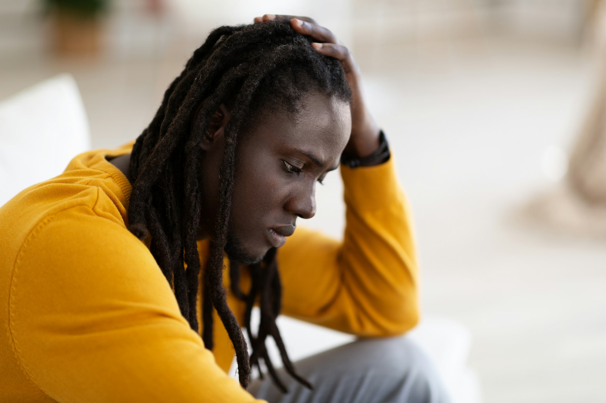 Depression. Portrait Of Upset Black Male With Dreadlocks Sitting At Home Alone