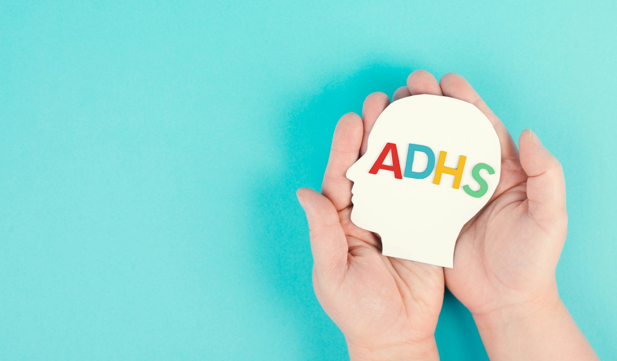 Hands holding a head with the german word ADHS which means attention deficit hyperactivity disorder